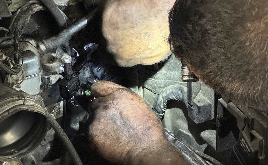 An experienced mechanic meticulously repairs a vintage car in a rustic, cluttered garage.